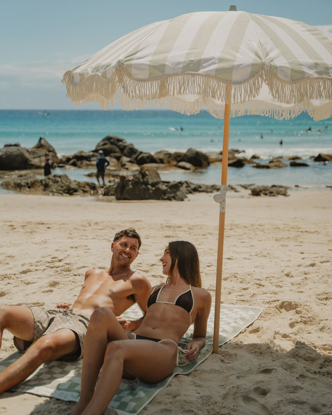 A couple lying back under a Beach Umbrella on the beach