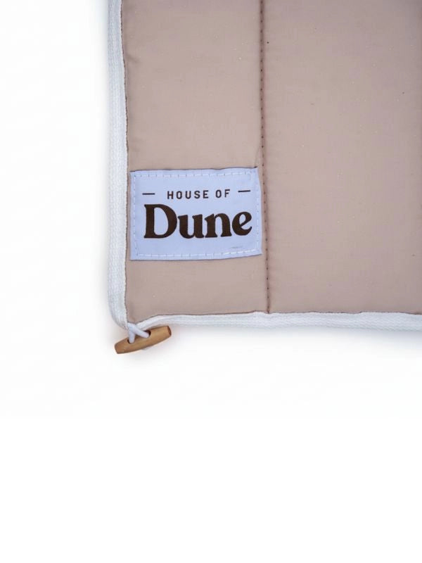 Close-up of the House of Dune label and toggle on the quilted Sand Drift beach lounger cover.