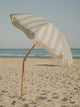 Salted Sage beach umbrella tilted in warm sunlight with subtle sage and white stripes, House of Dune coastal collection.