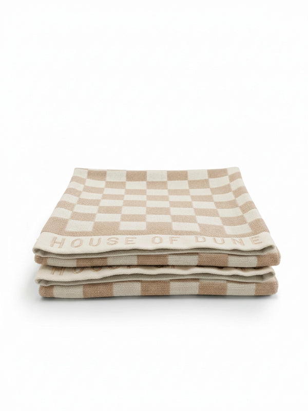 Set of two House of Dune Sand Drift beach towels with beige and white checkerboard design, neatly folded on a clean white background.