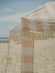 Detail shot of the House of Dune Sand Drift Cabana with wide neutral stripes and knotted fringe, capturing the soft coastal tones of the beach setting.