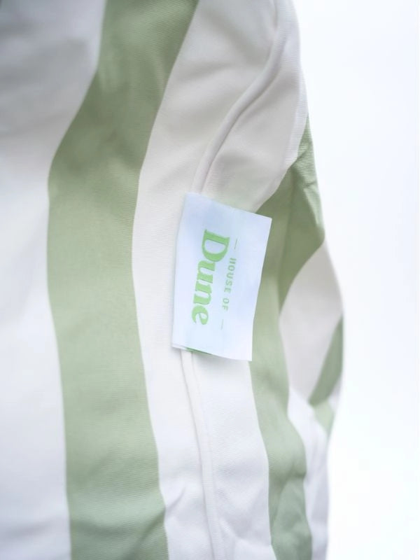 Close-up of the House of Dune label on the green and white striped fabric of the Salted Sage floating lounger.