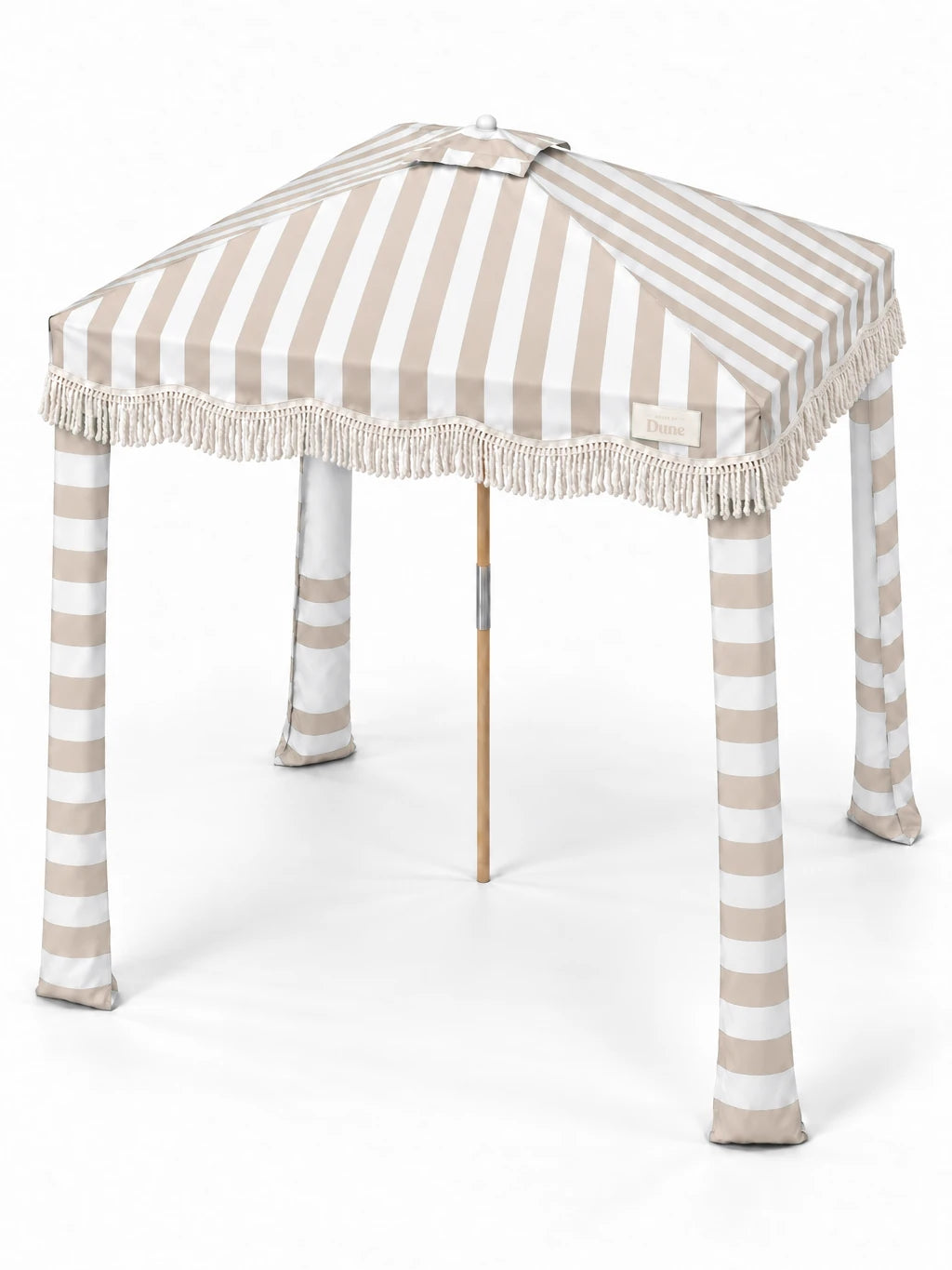 House of Dune Sand Drift beach cabana from a raised three-quarter angle, showing the striped roof panels, central vent, fringe and four fabric legs.