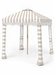 House of Dune Sand Drift beach cabana, three-quarter view on white: sand and white striped canopy with off-white fringe, striped fabric legs and wooden centre pole.