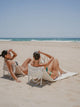 Oyster Tide and Sand Drift foldable beach loungers by House of Dune, crafted from recycled RPET, reclined on sandy shores facing the ocean for effortless beach comfort.