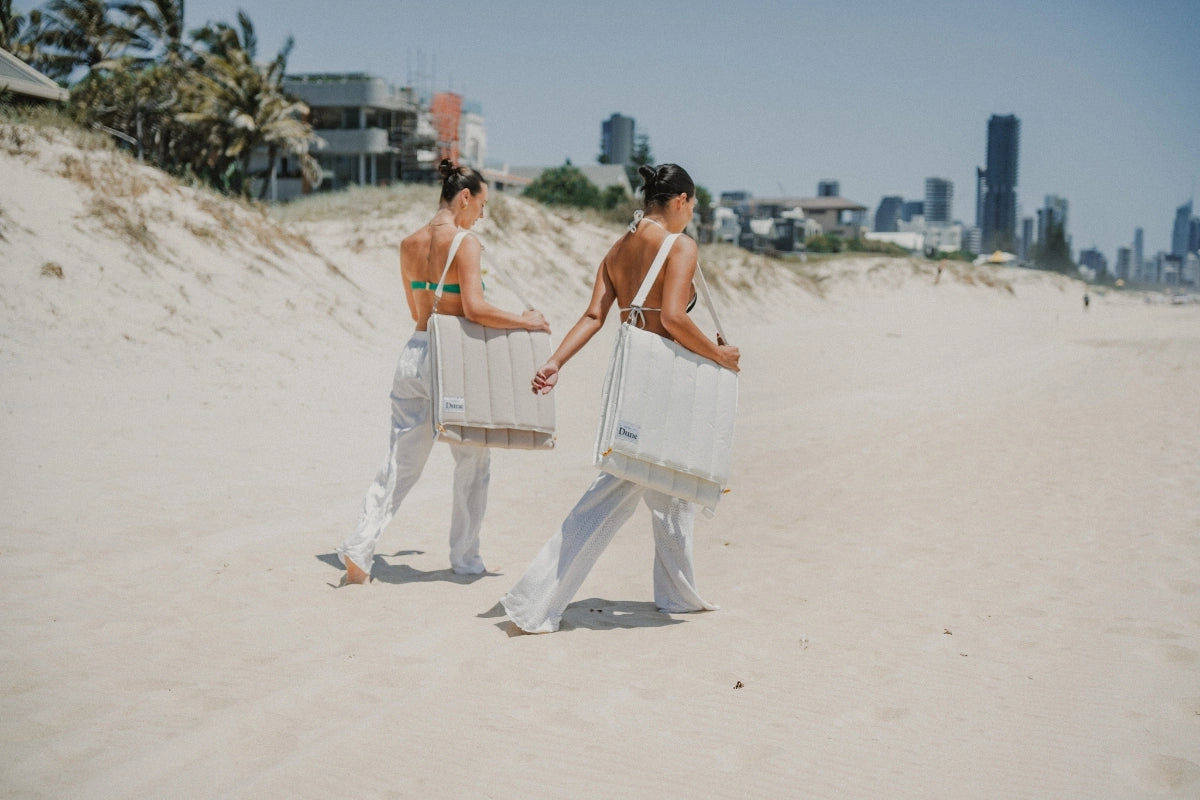 House of Dune beach loungers in Oyster Tide and Sand Drift colours, made from recycled RPET, carried hands-free across sand dunes in foldable backpack style.