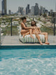 Couple sitting on the House of Dune Salted Sage floating lounger at the edge of a rooftop pool.