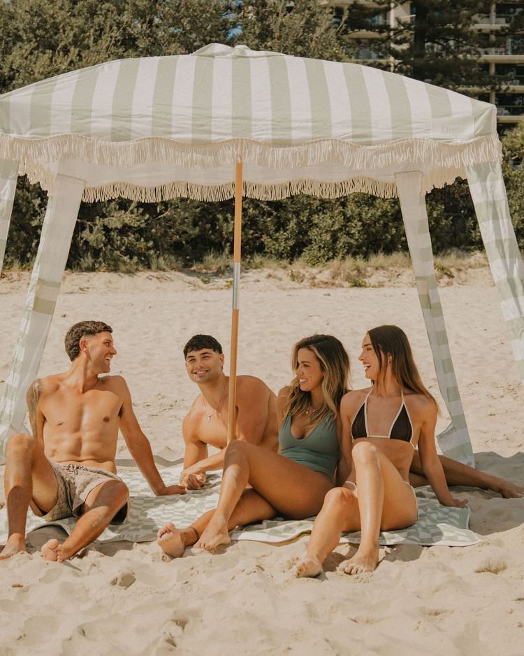 Friends relaxing in the shade of a Salted Sage Beach Cabana